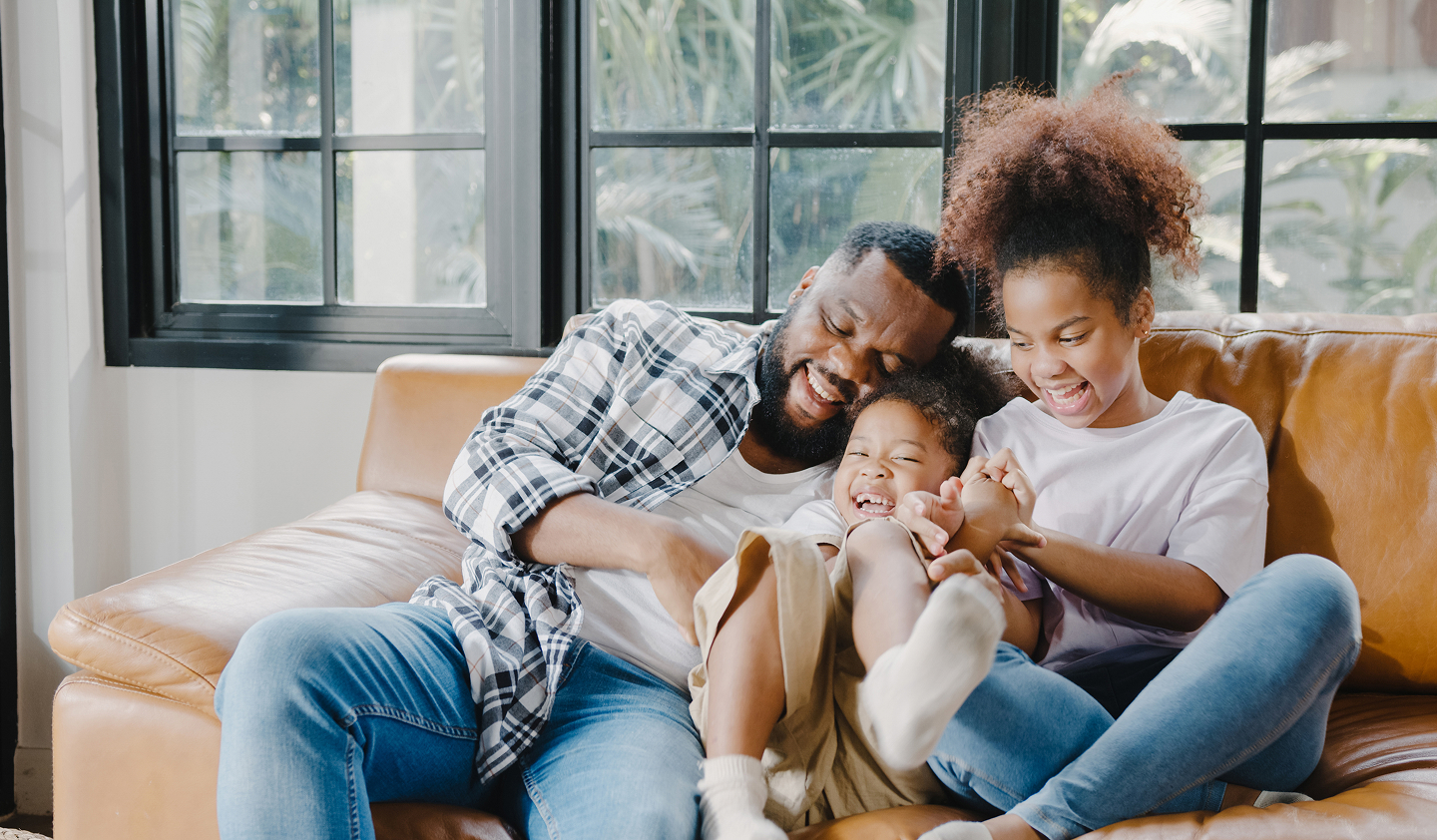 Smiling photo of a father and his children on the couch with great smiles.